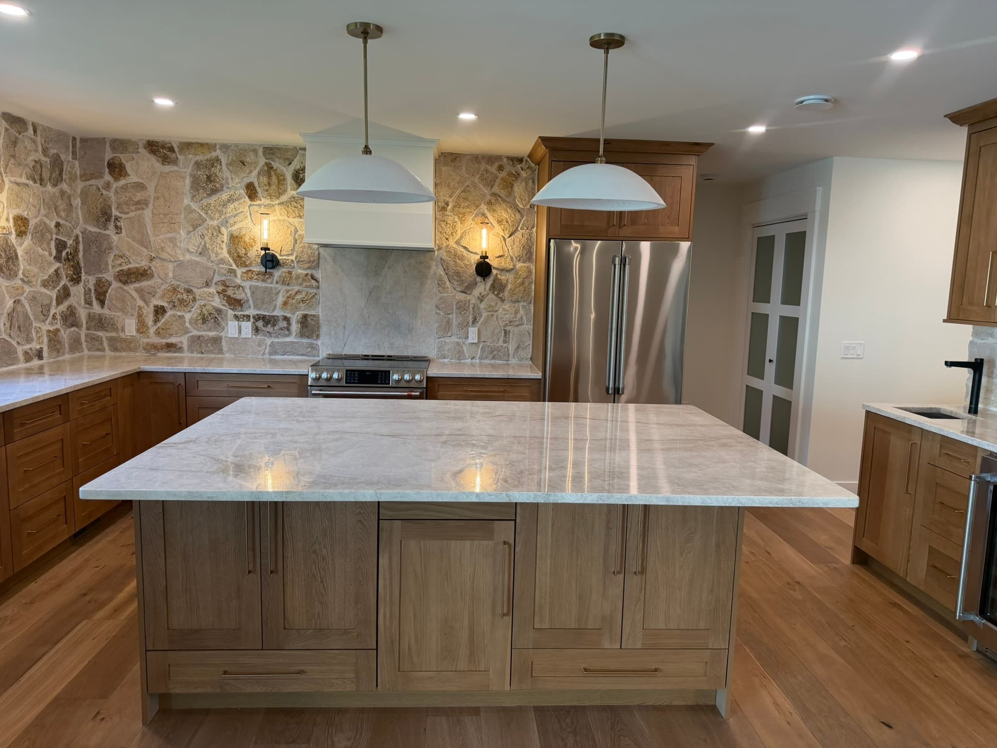 Kitchen with walnut cabinetry, a marble island, and pendant lighting