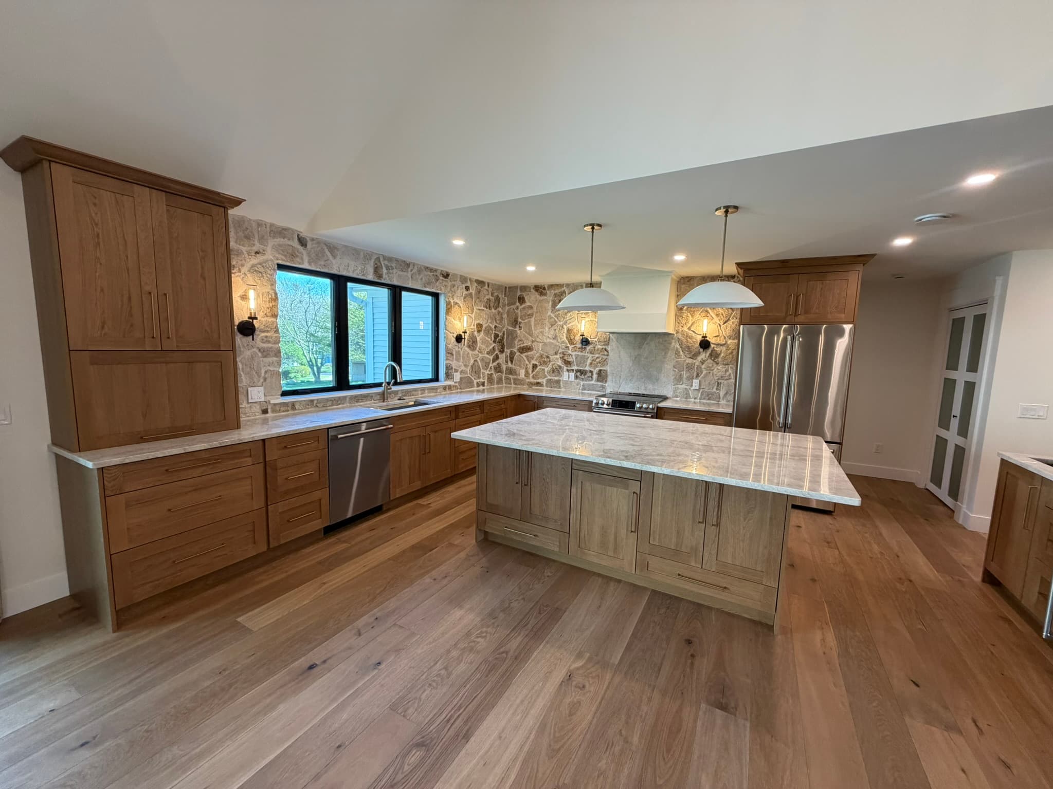 Kitchen from the dining side — walnut island, range, and stone backsplash