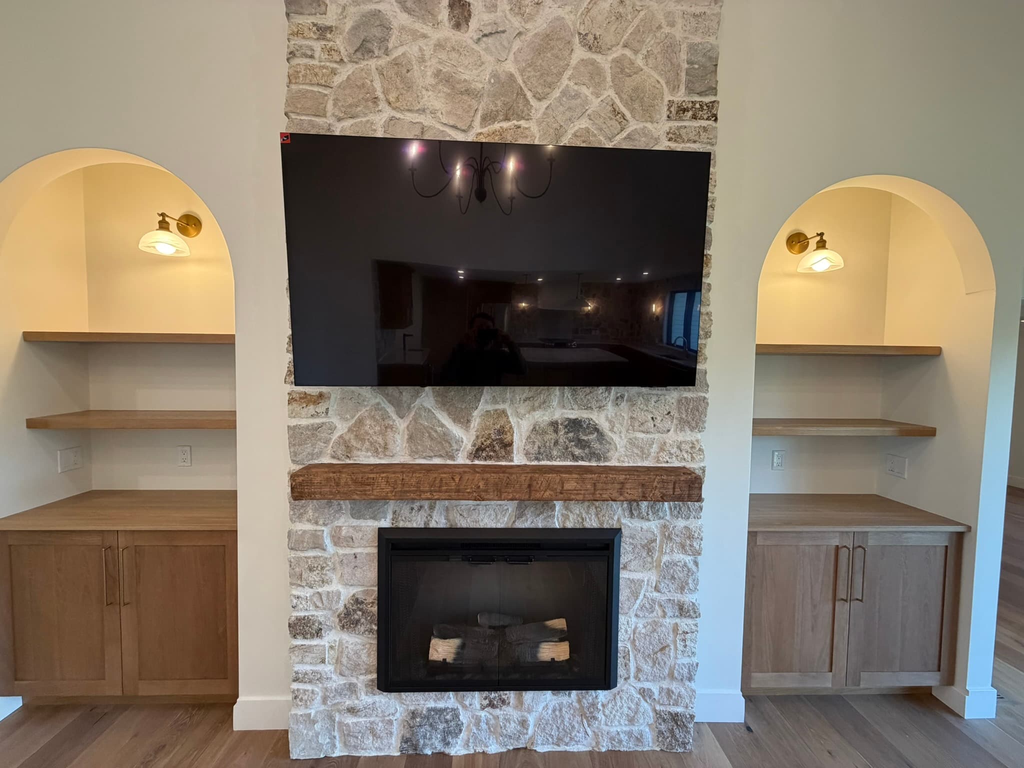 Electric stone fireplace flanked by arched built-in niches