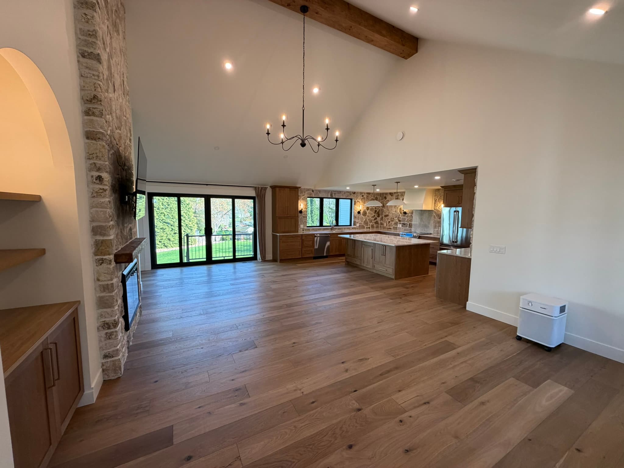 Open great room and kitchen with the electric stone fireplace and black-framed windows