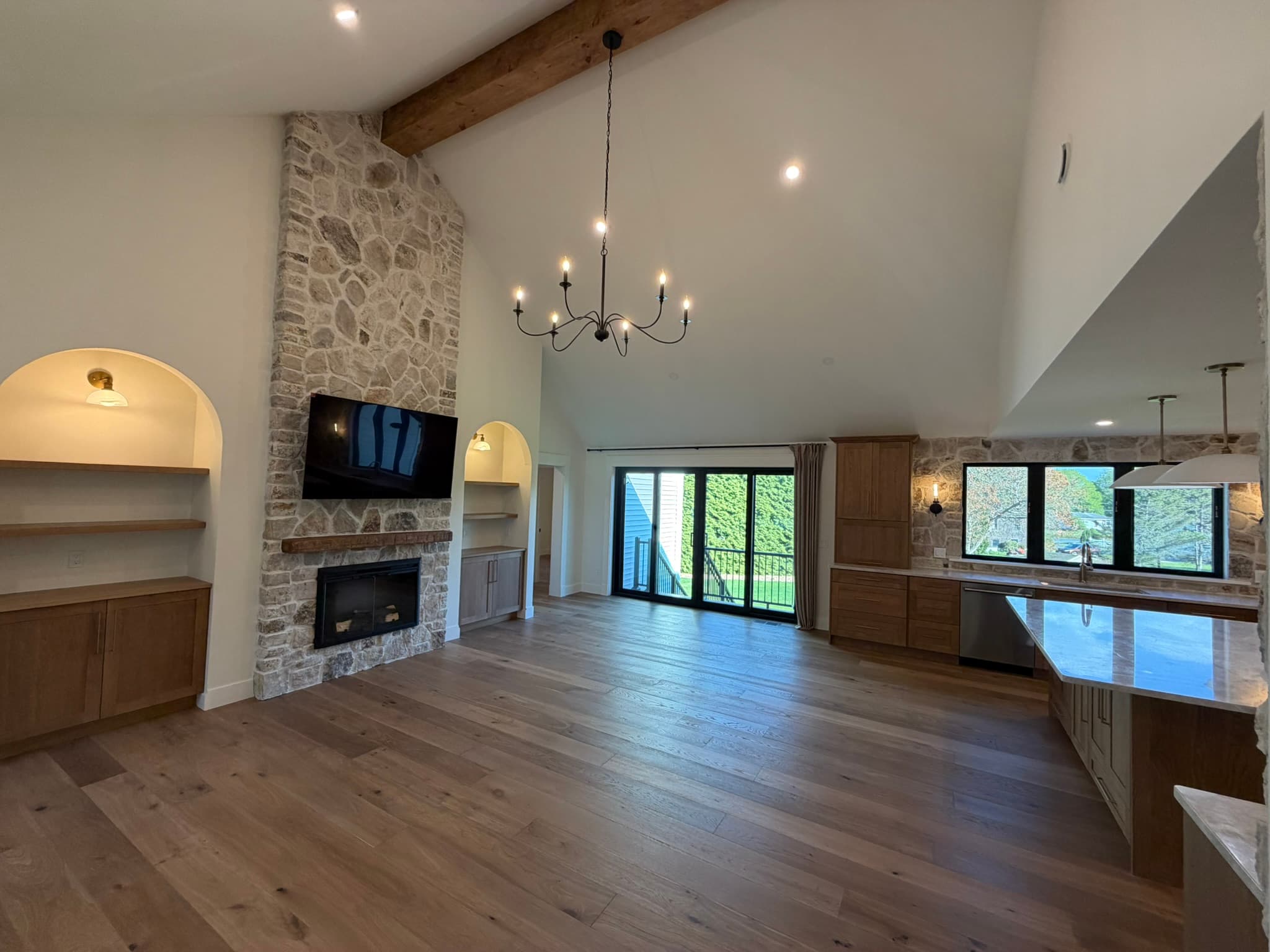 Open living and kitchen with wide-plank floors and the electric stone fireplace