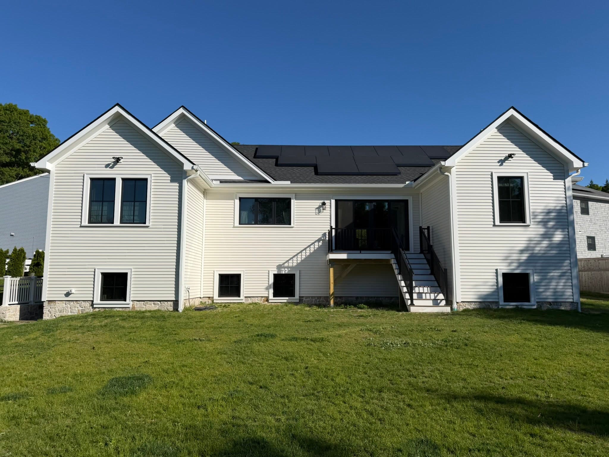 Rear elevation of 60 Rockland Drive showing the 20 kW rooftop solar array, deck, and walkout basement